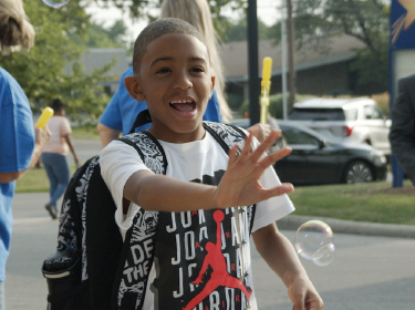 student waving into camera